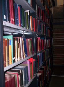 Photograph of shelving holding books of many colours and sizes.