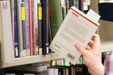student takes book from shelf in the Library