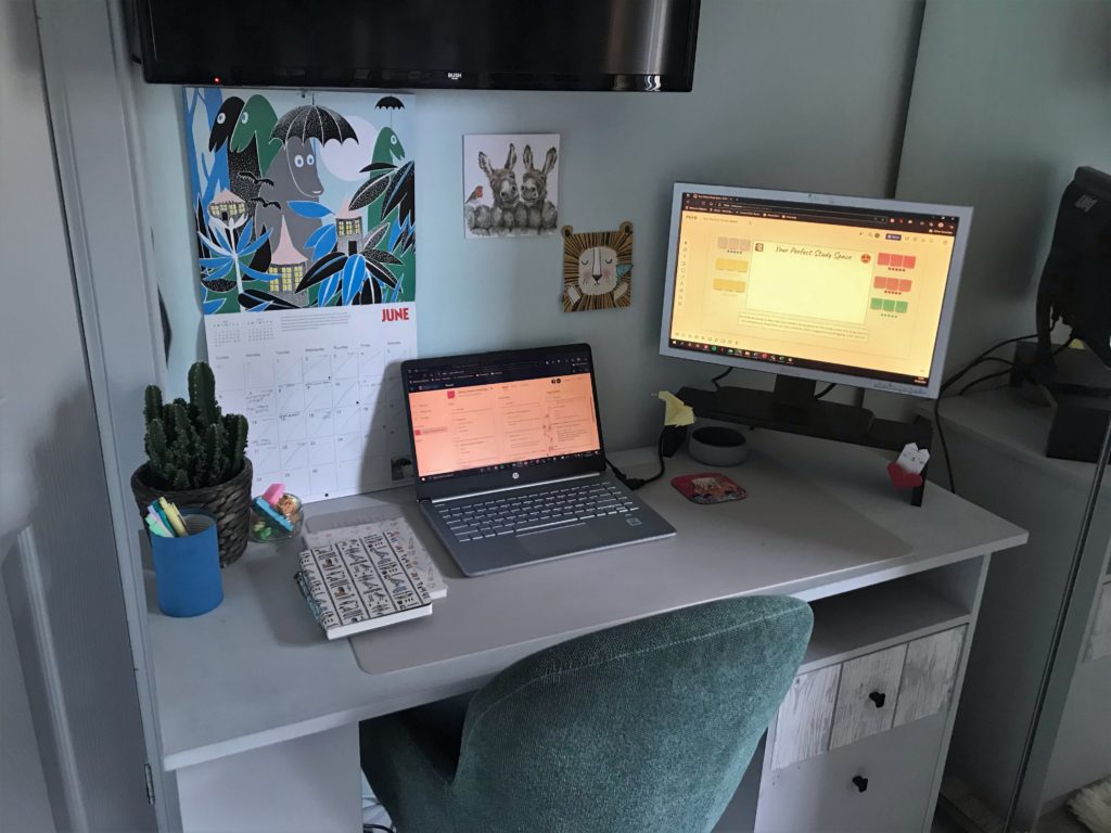 Photo of desk with laptop, monitor, calendar and notebook
